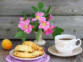 Tasty croissants with cup of coffee on brown wooden background