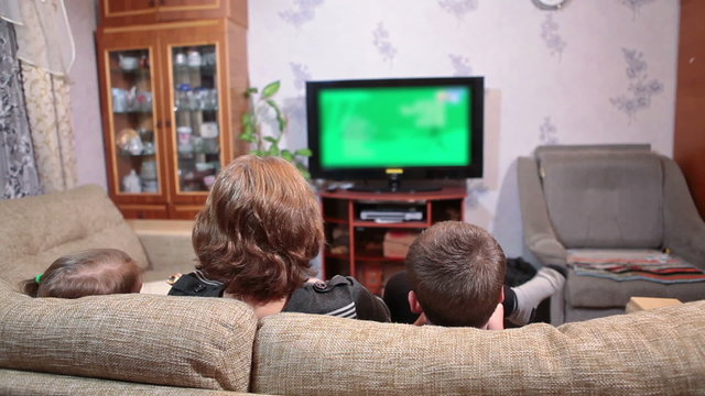 Small kids watching cartoons on lcd tv with their mother, sitting on sofa