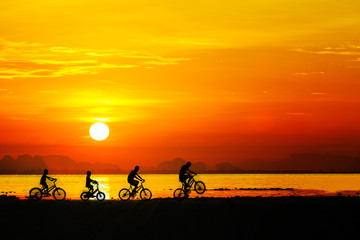 Fototapeta na wymiar Silhouettes of childrens on bicycle against sunset sky at the be