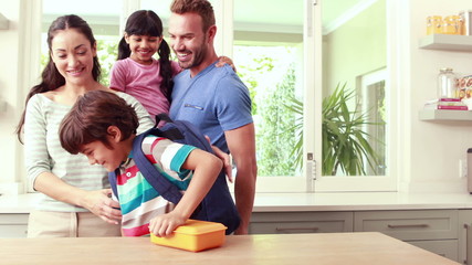 Mother giving to her son lunch box
