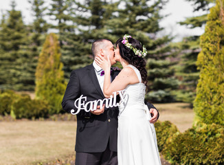 bride and groom holding bouquet and wooden word family