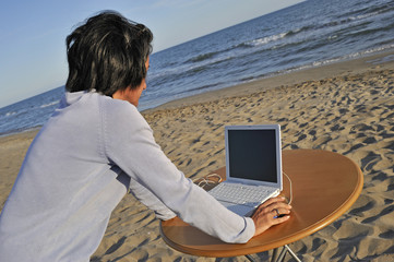 Mid-adult woman using a laptop on the beach