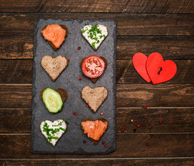 Canapes heart shape with different toppings on black slate board