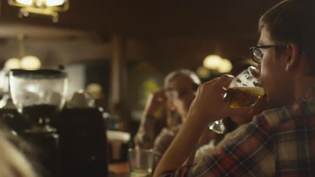 Friends laugh, drink beer and cocktails while having a good time together at a bar. Shot on RED Cinema Camera.