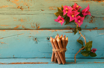 stack of wooden colorful pencils on wooden texture table next to purple bougainvillea flower
