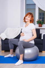 happy pregnant woman exercising on fitball at home