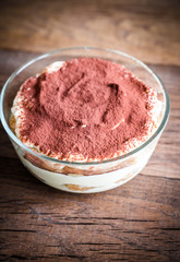Tiramisu in the glass bowl on the wooden background