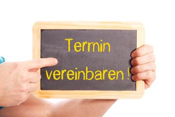 Zeigefinger zeigt auf Kreidetafel mit TERMIN VEREINBAREN