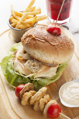 Delicious hamburger and french fries and onion rings on wooden b