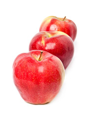 three red apples stand in one row on a white background