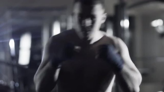 Professional male boxer is training punches and kicks in dark gym. Shot on RED Cinema Camera.