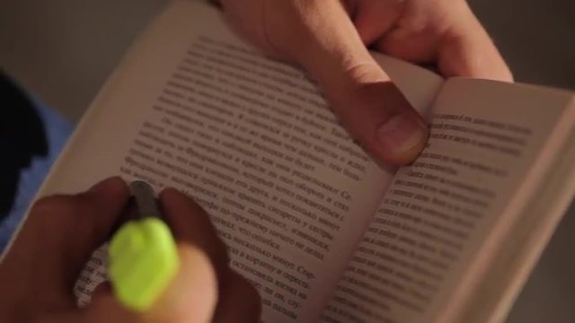 Мужчина держит в руках книгу и отмечает маркером страницы