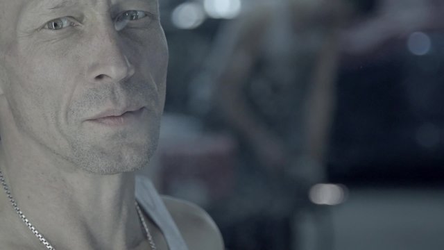 Portrait of a working auto mechanic smoking cigarette in garage in slow motion