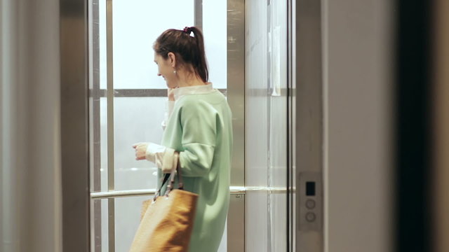 Woman talking on the phone and enters the elevator