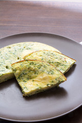 Omelet with spinach and zucchini with melted cheese on brown pla