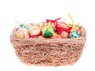 Fototapeta na wymiar Easter eggs in a straw basket on the white