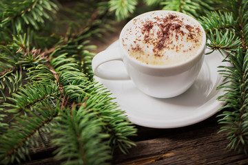 Obraz na płótnie Canvas A cup of coffee with the branches of the Christmas tree on a woo