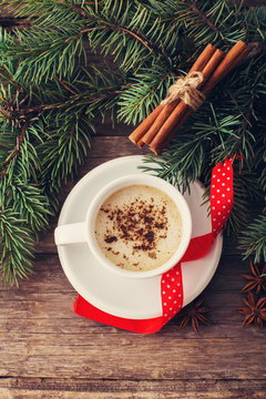 A cup of coffee with the branches of the Christmas tree on a woo