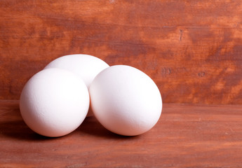 three white eggs on the wooden background