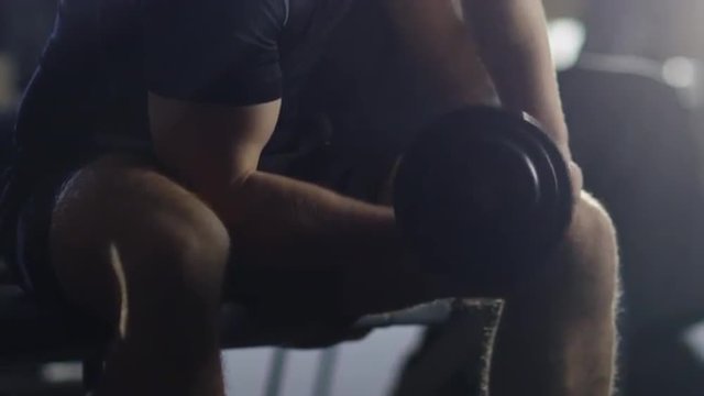 Handsome fit sporty man is exercising with heavy dumbbell in the gym. Shot on RED Cinema Camera.