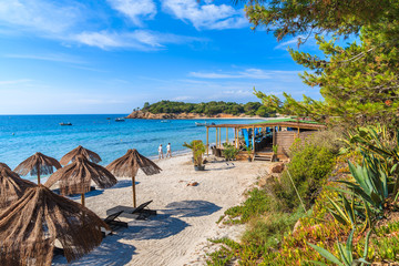 Een paar mensen die langs het strand van Palombaggia lopen met een restaurantgebouw op de achtergrond, het eiland Corsica, Frankrijk
