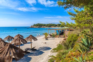 Vlies Fototapete Palombaggia Strand, Korsika Paar Leute zu Fuß am Strand von Palombaggia mit Restaurantgebäude im Hintergrund, Insel Korsika, Frankreich