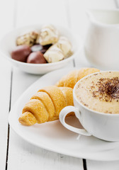Hot cappuccino and pastries on white wooden boards