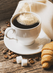 Close-up of coffee cup with roasted coffee beans on wooden backg