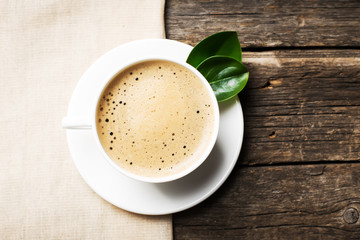 Close-up of coffee cup with roasted coffee beans on wooden backg