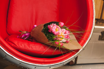 Bouquet of pink peonies on red-steel chair