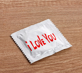 Condom with text I love you on wooden table