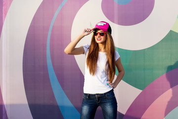 Girl standing against a background of multicolored wall street fashion style.