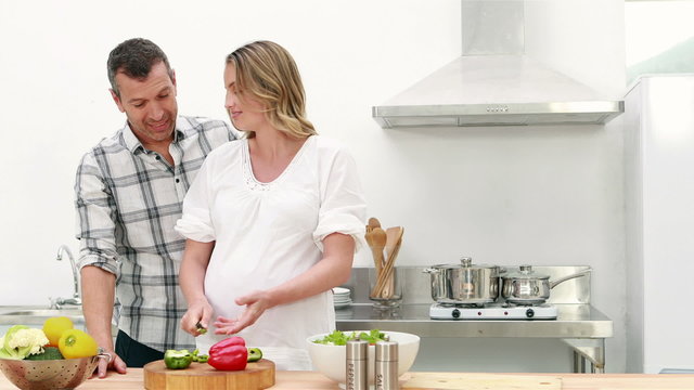 Pregnant woman making a salad with her husband