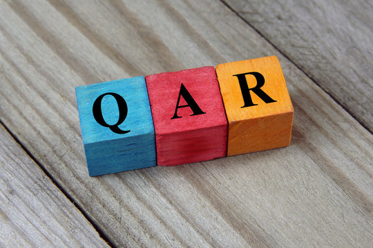 QAR (Qatari Riyal) sign on colorful wooden cubes