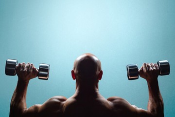 Fototapeta na wymiar Composite image of rear view of muscular man lifting dumbbells