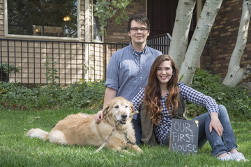 couple in front of new home as new homeowners excited for their purchase