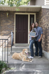 couple in front of new home as new homeowners excited for their purchase