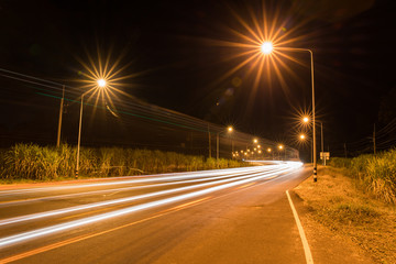 Fototapeta na wymiar Night Road at suburban with the light trails car - Night transportation and ray of a star 