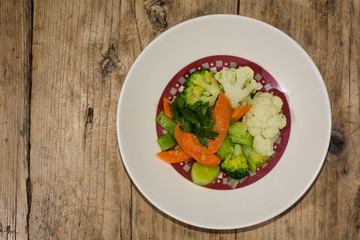 Steamed vegetables on a white plate, from above. A side dish of brightly coloured vegetables, prepared by a French chef
