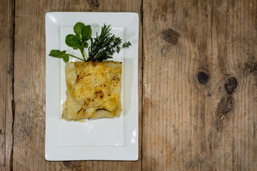 Dauphinois potato from above. Classic French vegetable dishes, with garnish on white plates
