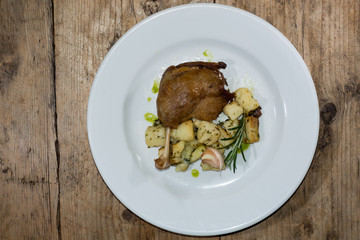 Duck confit with salardaise potatoes, from above. Classic French dish with herbs, garlic and potatoes cooked in goose fat
