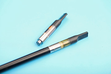 Cannabis oil dispenser/electronic cannabis oil vaporizer with oil-filled cartridge on wood surface