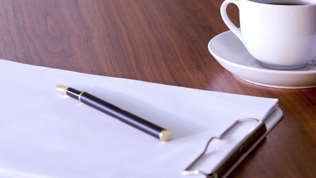 Documents, pen and cup on table