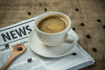 A newspaper and a cup of coffee on a wooden table