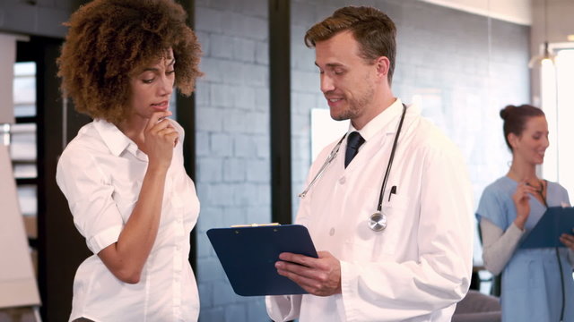 Doctor speaking with nurse while looking clipboard