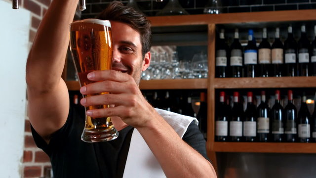 Smiling barman pulling a pint of beer 
