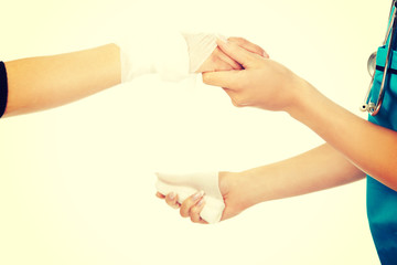 Female doctor bandaging woman hand