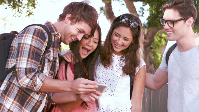 Hipster friends laughing while looking smartphone