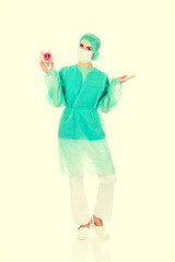 Female surgeon doctor holding piggy bank