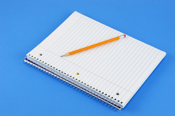 blank notebook with pencil on blue background